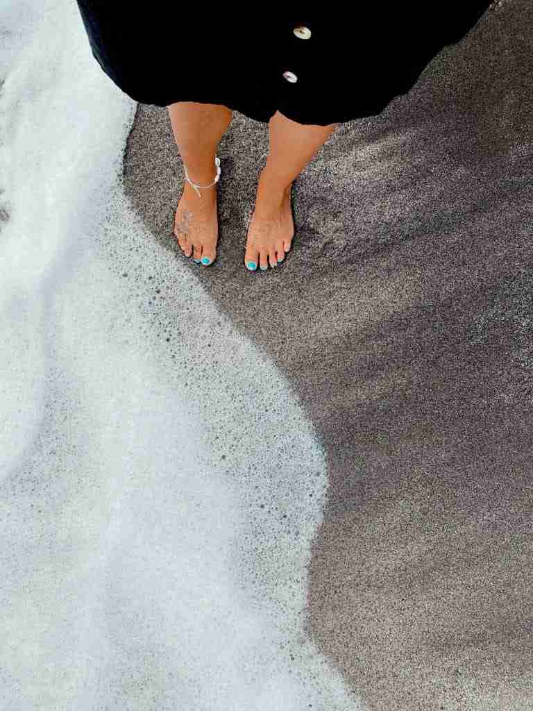 feet on black sand Sabiwsha beach in st lucia representing the different beaches in st lucia to visit