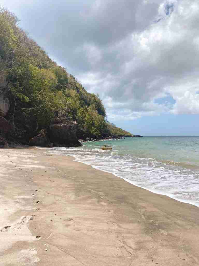 white sand and anse galet beach backed by tall cliff in st lucia
